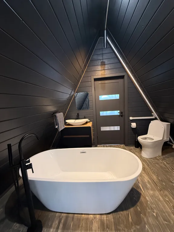 Большой треугольный домик с камином, с ванной у окна с видом на лес