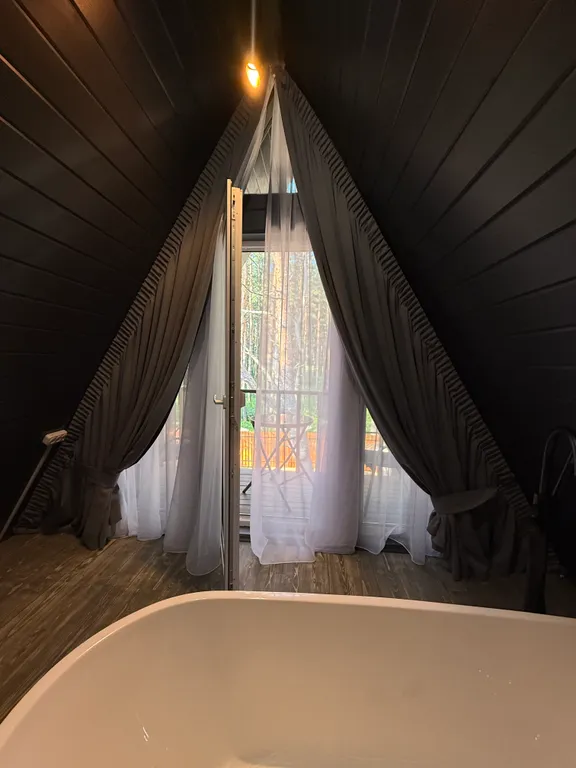 Большой треугольный домик с камином, с ванной у окна с видом на лес