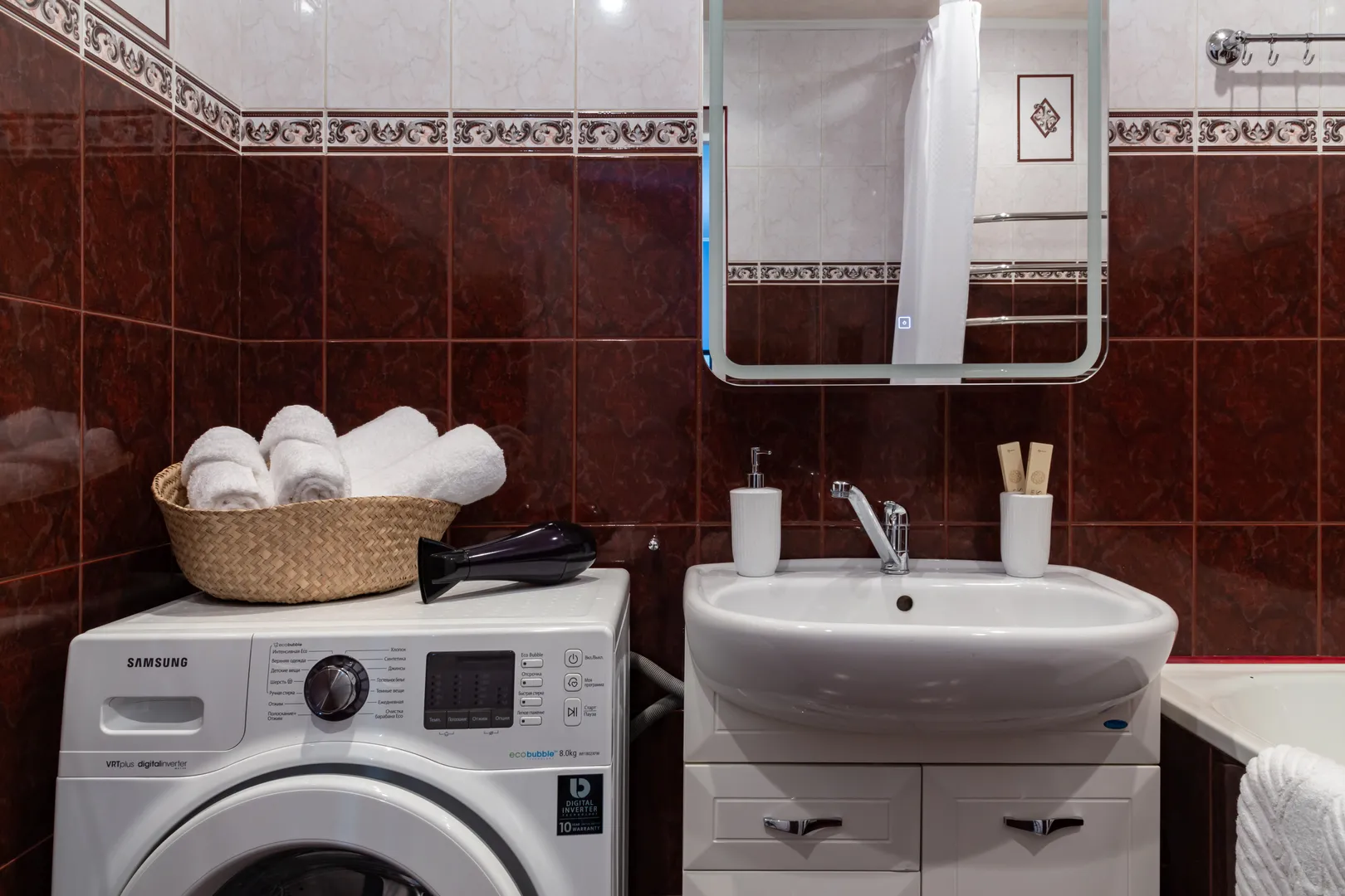 Ванная комната с белоснежными полотенцами, феном, стиральной машиной, косметическими средствами и водонагревателем