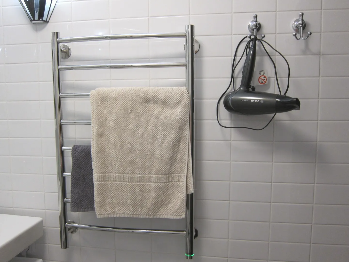 Электрический полотенцесушитель и фен в ванной комнате.