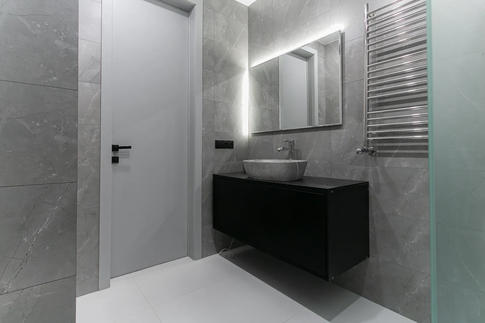 Ванная комната оборудована встроенным унитазом, гигиеническим душем, раковиной, тумбой с выдвижными ящиками, просторным душем, полотенцесушителем, зеркалом с подсветкой
