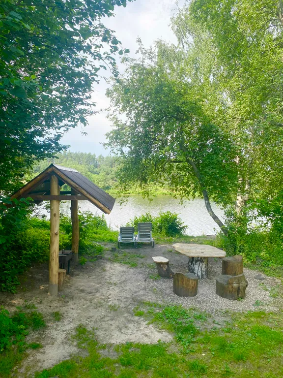 Деревянный дом на берегу реки с беседкой