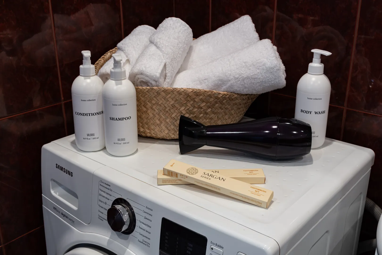 Ванная комната с белоснежными полотенцами, феном, стиральной машиной, косметическими средствами и водонагревателем