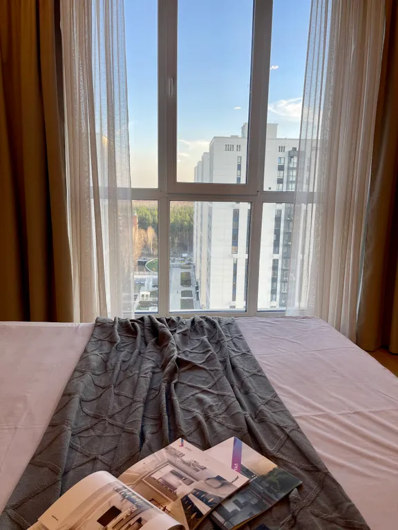 Новая квартира с кроватью возле панорамного окна, высокий этаж