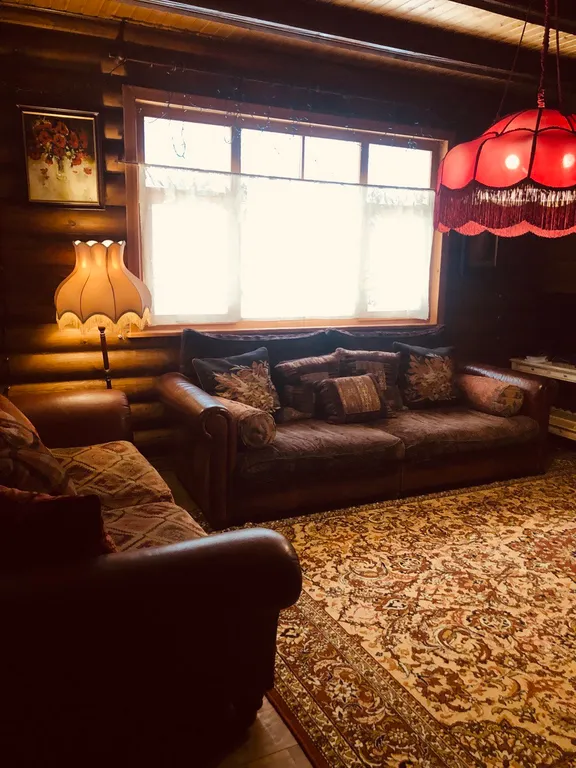 Изба (дом) из экологически чистого бревна под камышовой крышей в лесу