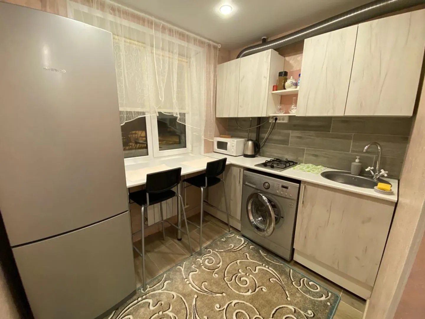 Уютная кухня. Есть микроволновая печь, холодильник, электрический чайник, газовая плита и стиральная машина 