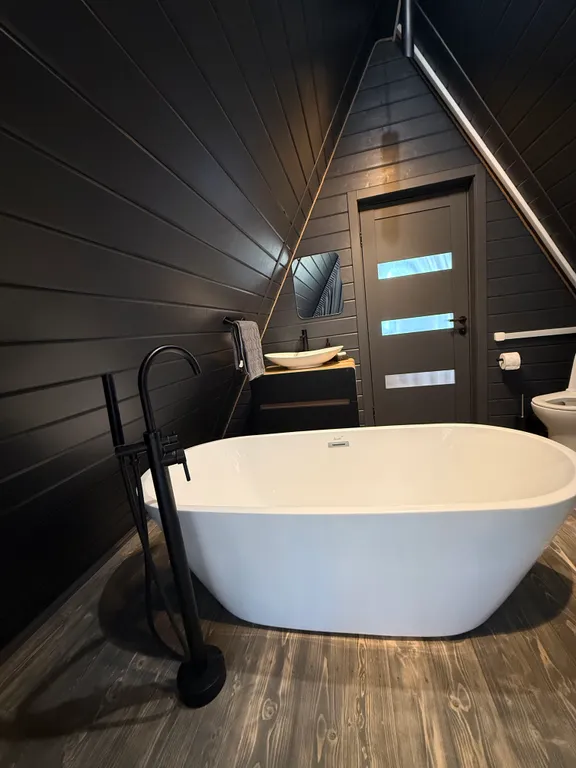 Большой треугольный домик с камином, с ванной у окна с видом на лес