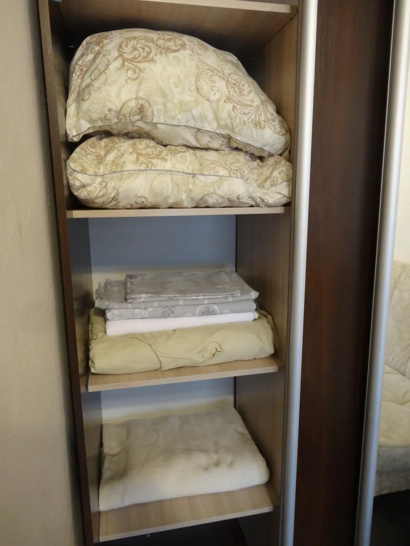 В левой части шкафа хранятся постельные принадлежности для двухспального дивана и комплект постельного белья, а также плед.