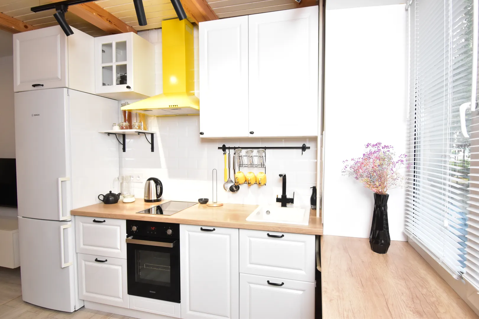 На фото — наша элегантная кухонная зона, окутанная мягким светом, с красивыми посудой и стаканами, создающими атмосферу настоящего уюта. 