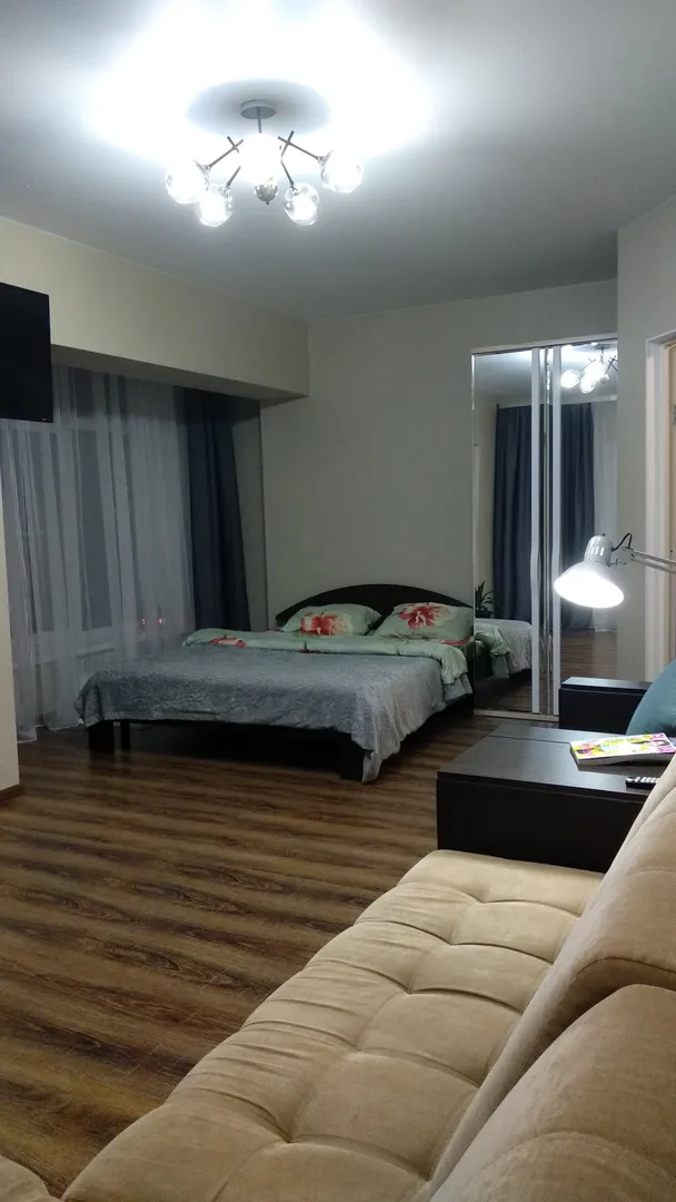 Вместительная спальня с панорамными окнами,  двуспальной кроватью, раскладывающимся диваном и шкафом с зеркалом.