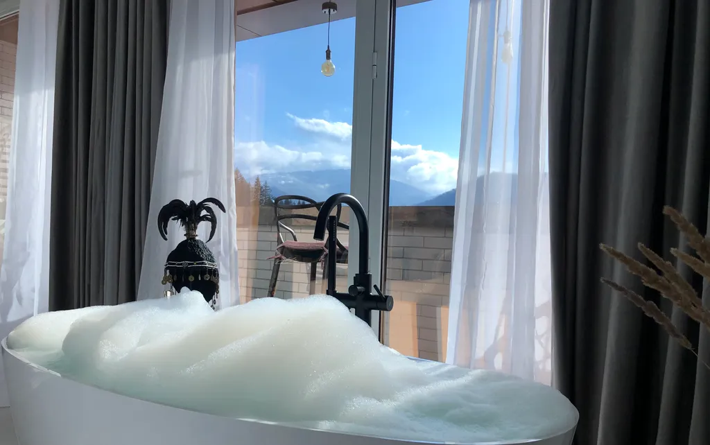 Стильная студия с ванной у панорамного окна и видом на горы