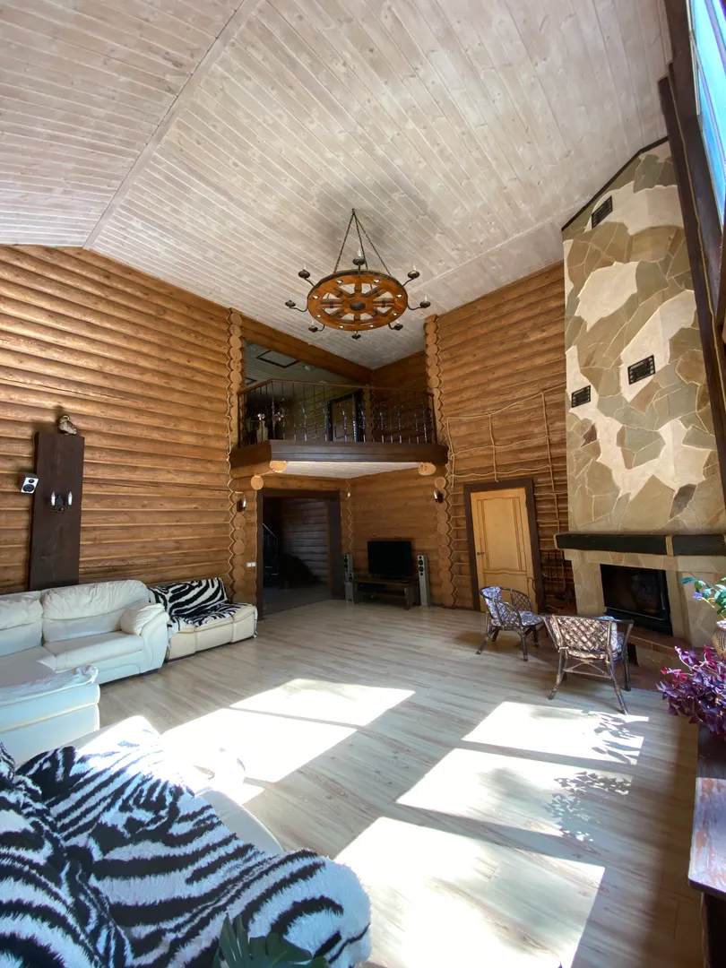 Просторная гостиная с витражными окнами от пола до потолка, камином и выходом на веранду 