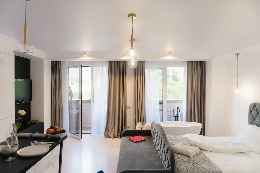 Стильная студия с ванной у панорамного окна и видом на горы