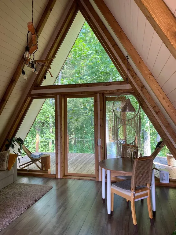 Лесной домик a-frame с террасой на холме, среди высоченных елей и берез