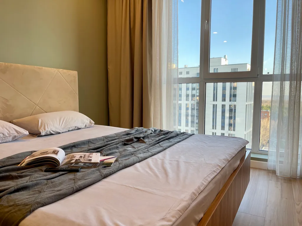 Новая квартира с кроватью возле панорамного окна, высокий этаж