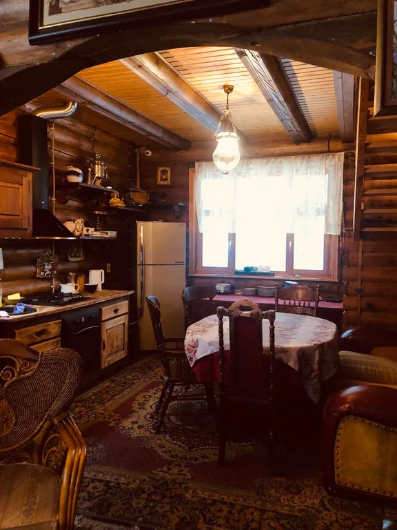 Изба (дом) из экологически чистого бревна под камышовой крышей в лесу