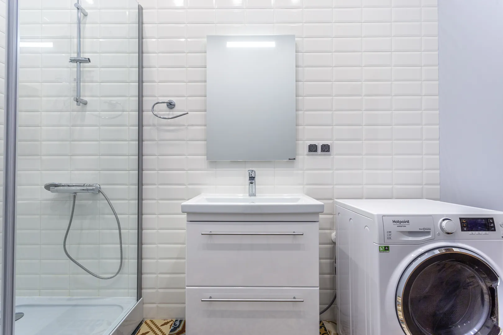Стиральная машина большой загрузки с функцией сушки находится в ванной комнате. Зеркало с подсветкой.