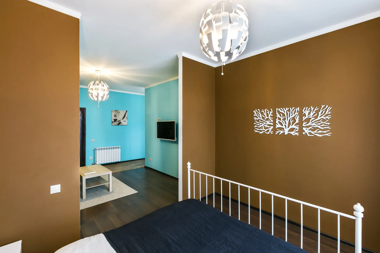 Спальная зона в белых тонах на фоне стен шоколадного оттенка, одну из которых украшает панно авторской работы.