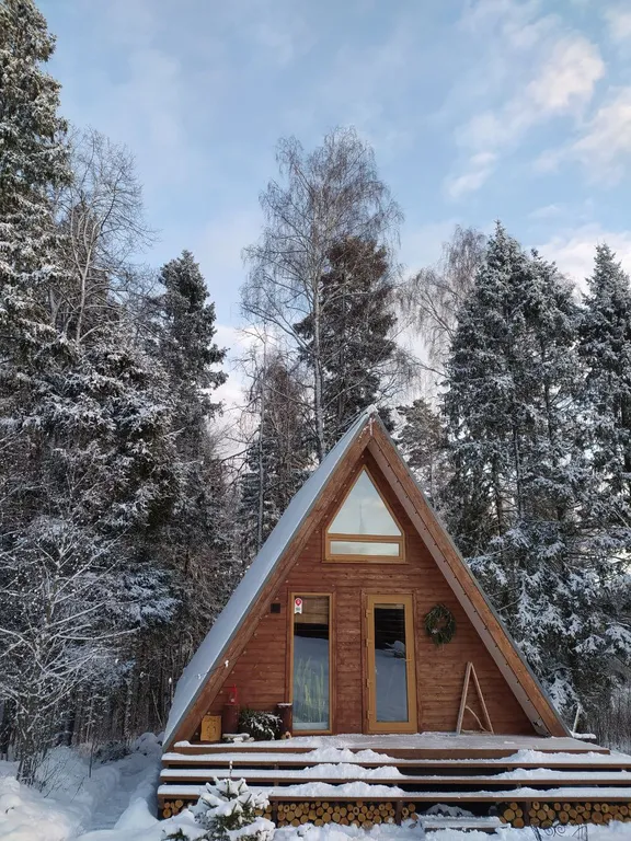 Лесной домик a-frame с террасой на холме, среди высоченных елей и берез