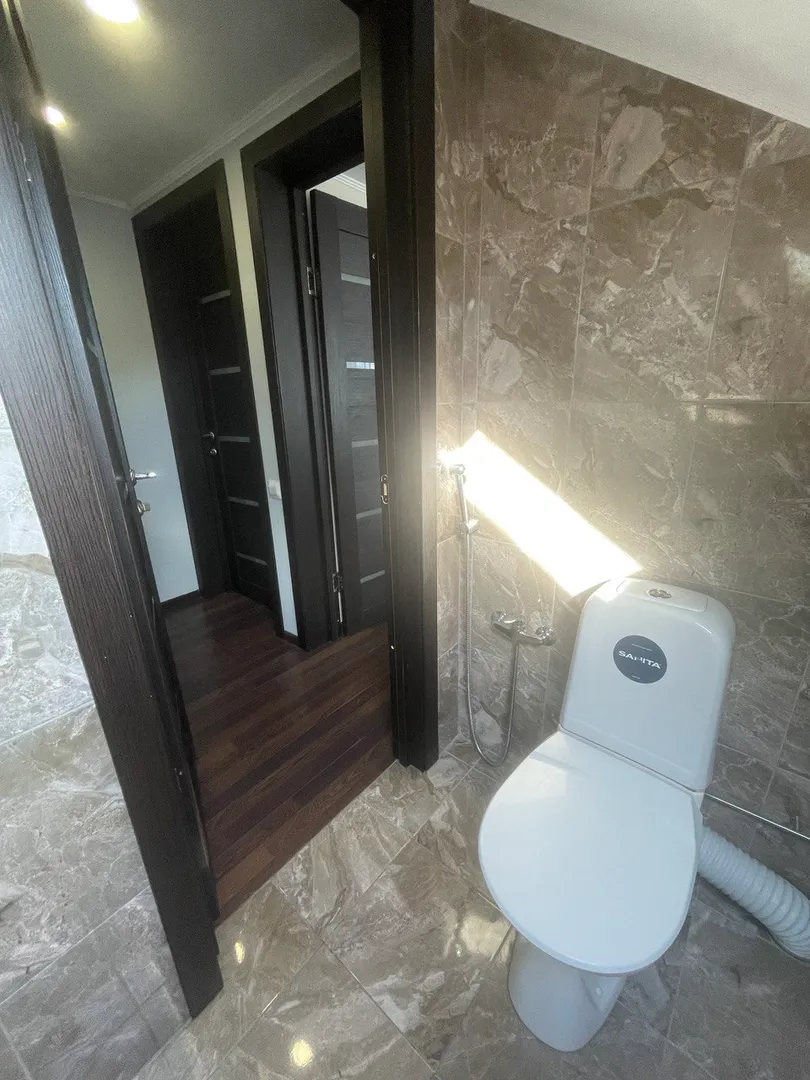 Туалет с раковиной и гигиеническим душем на 2-ом этаже. На заднем плане двери в спальни 