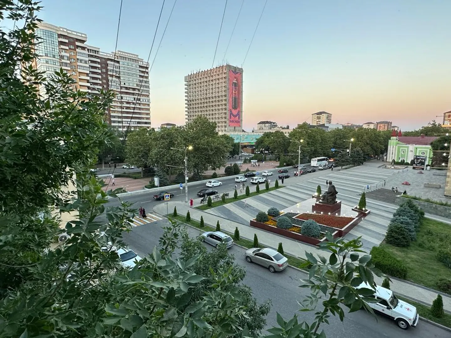 Вид с балкона на центральный проспект, супермаркет Зелёное Яблоко, гостиницу Ленинград и памятник поэту Расулу Гамзатову