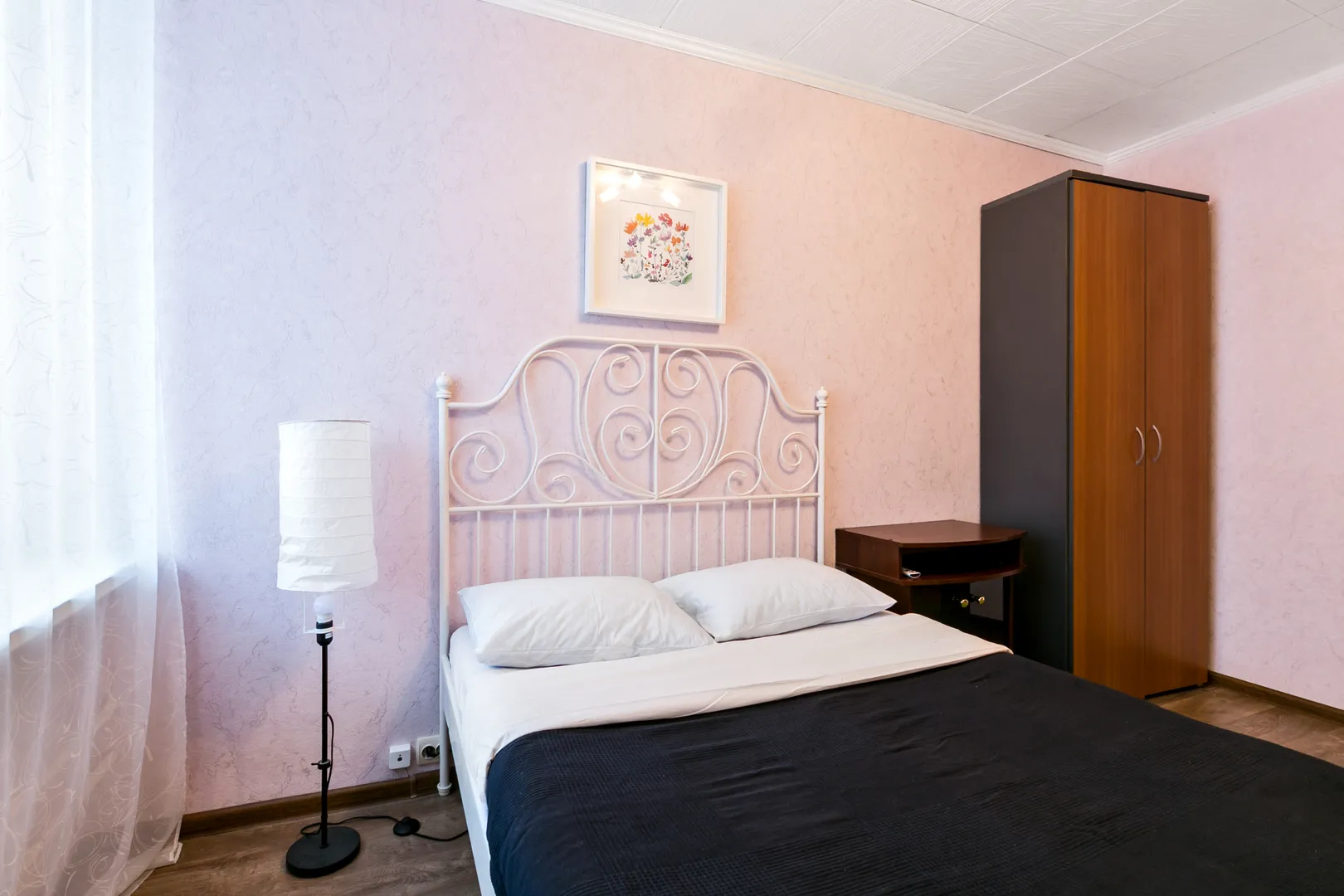 Спальня: крепкая железная кровать с чистым матрасом и застеленным бельем, ЖК-телевизор, плотные шторы и мягкий ковер.
