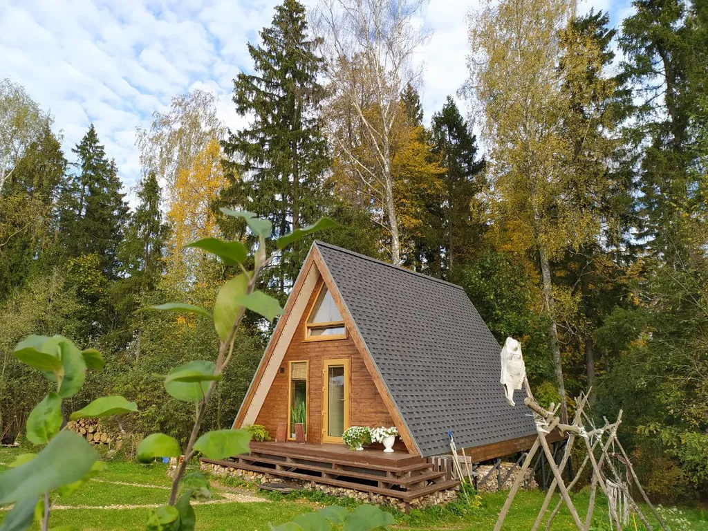 Лесной домик a-frame с террасой на холме, среди высоченных елей и берез