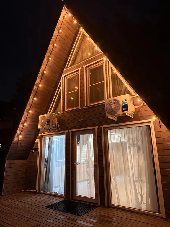 Большой треугольный домик с камином, с ванной у окна с видом на лес