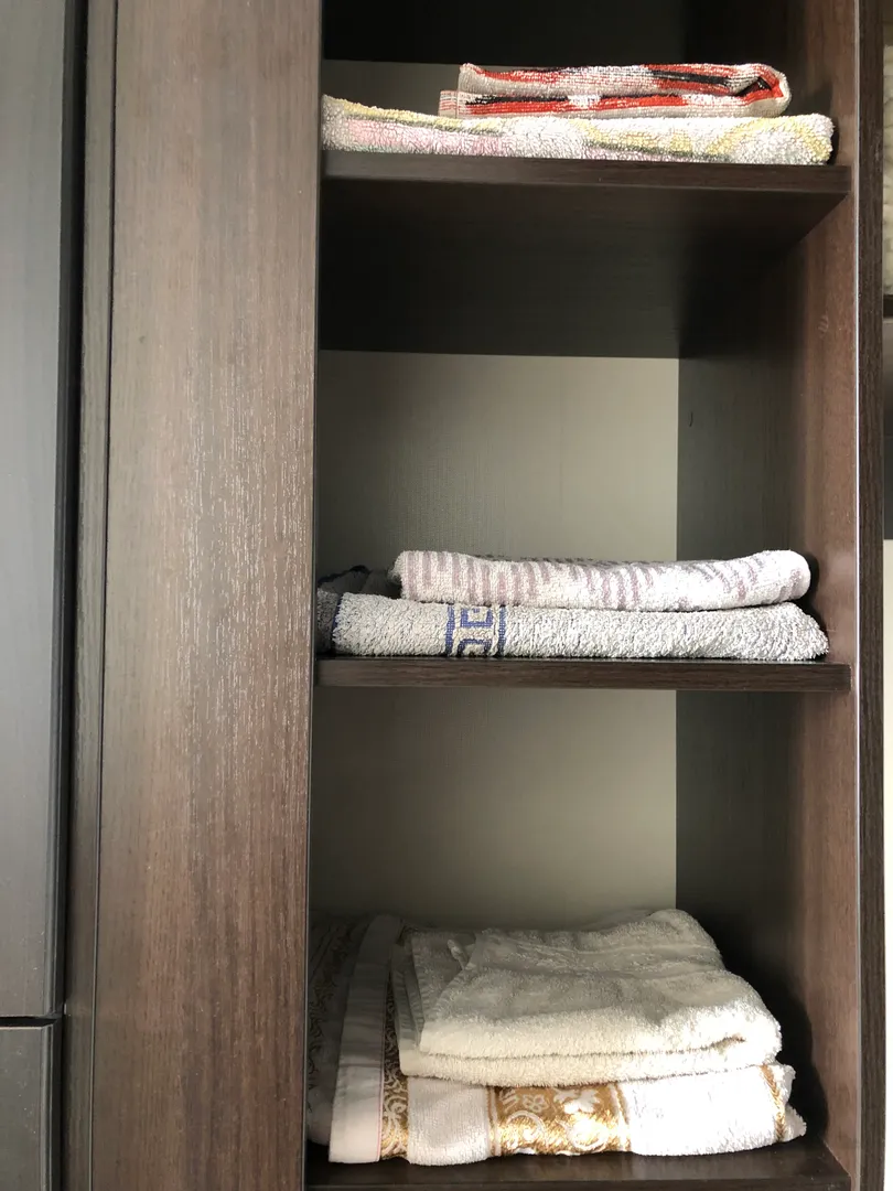 Вместительный шкаф-купе с полками и полотенцами разных размеров.