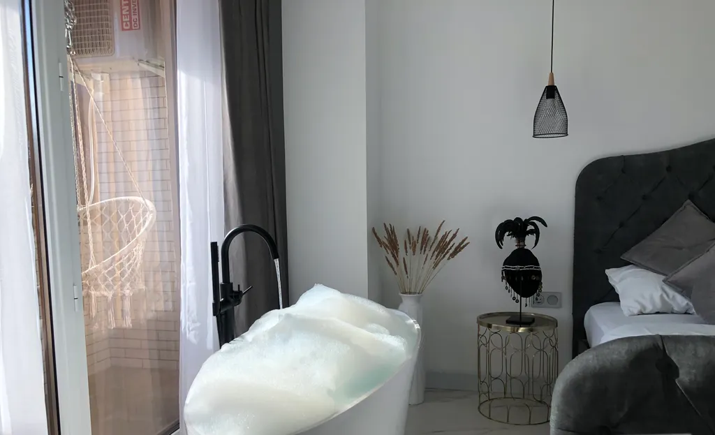 Стильная студия с ванной у панорамного окна и видом на горы