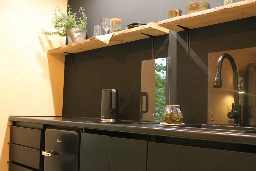 Дом с ванной у панорамных окон и высокой террасой в лесу