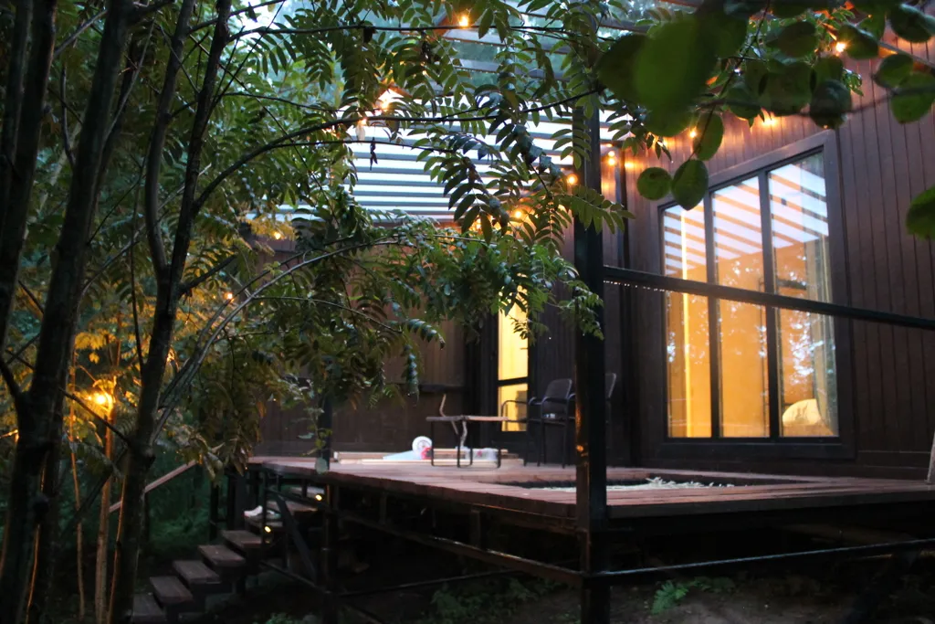 Дом с ванной у панорамных окон и высокой террасой в лесу