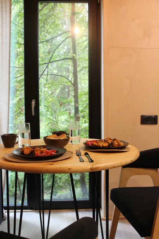 Дом с ванной у панорамных окон и высокой террасой в лесу