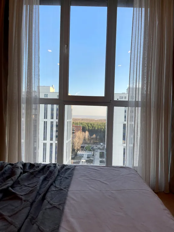 Новая квартира с кроватью возле панорамного окна, высокий этаж