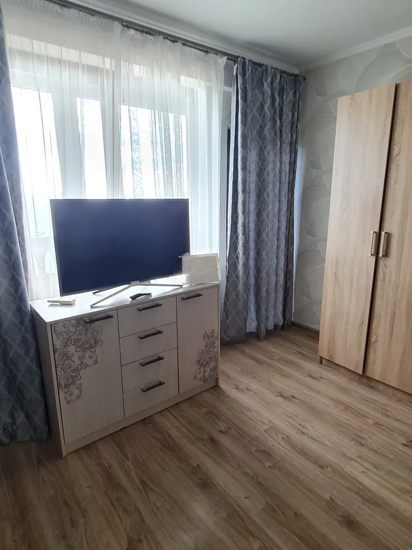 Телевизор, шкаф, дверь, которая ведёт на открытый балкон