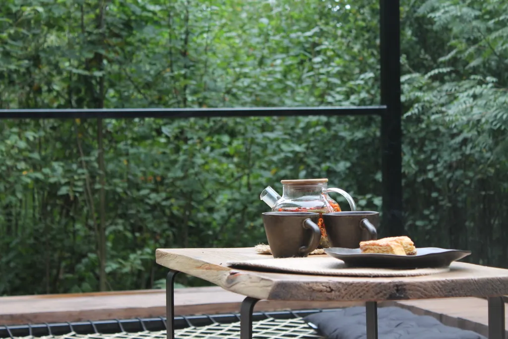 Дом с ванной у панорамных окон и высокой террасой в лесу