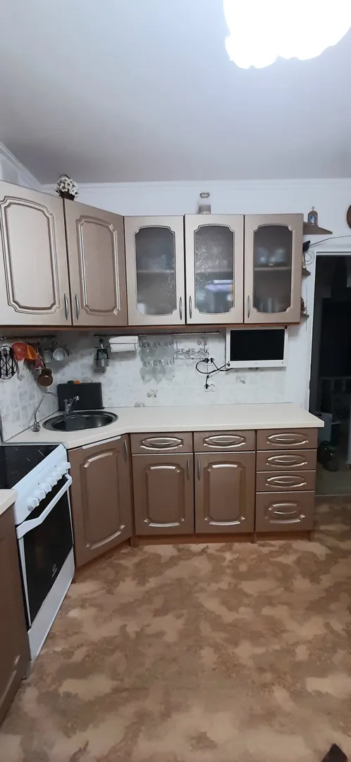 Кухонный гарнитур, плита, раковина, телевизор.