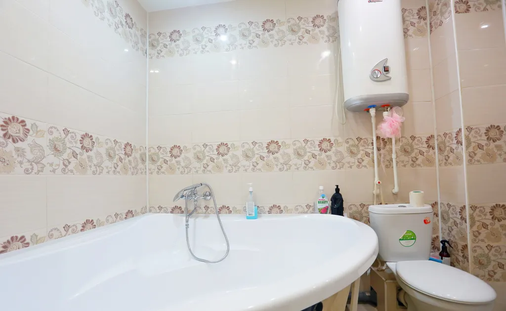 Уютная студия в тёплых тонах с большой угловой ванной для пары