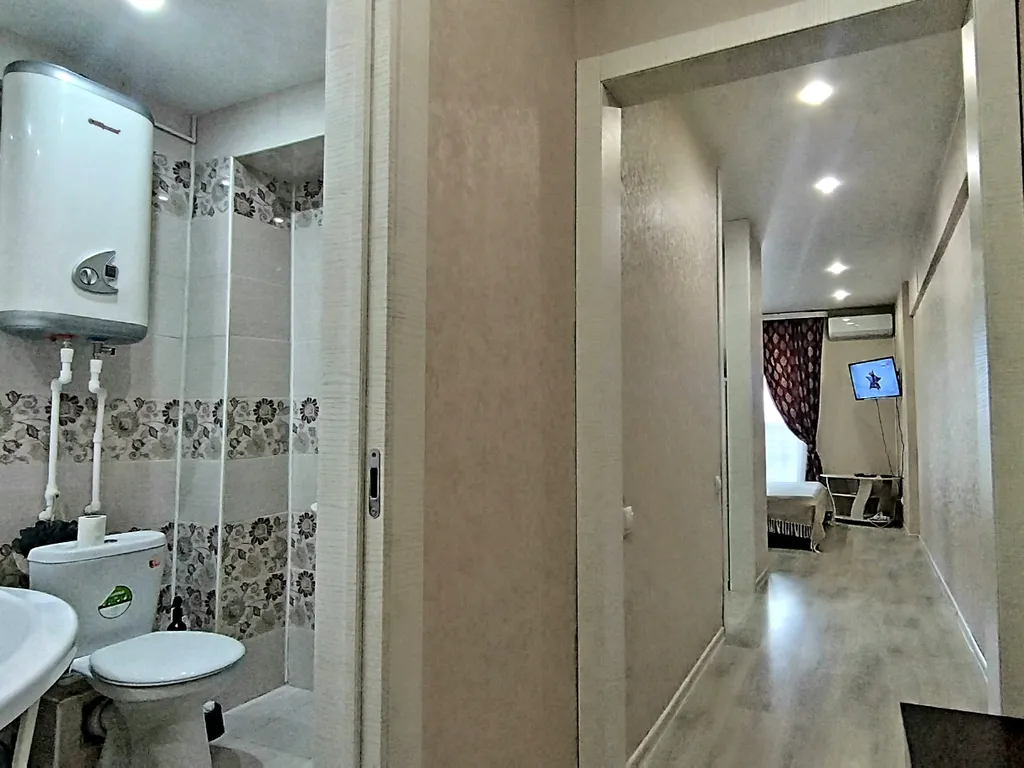 Уютная студия в тёплых тонах с большой угловой ванной для пары