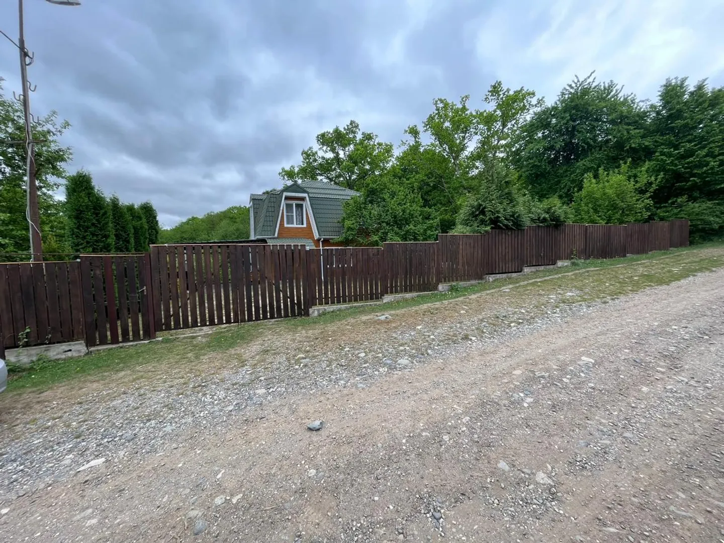 Общий вид на дом за забором Общий вид на дом за забором