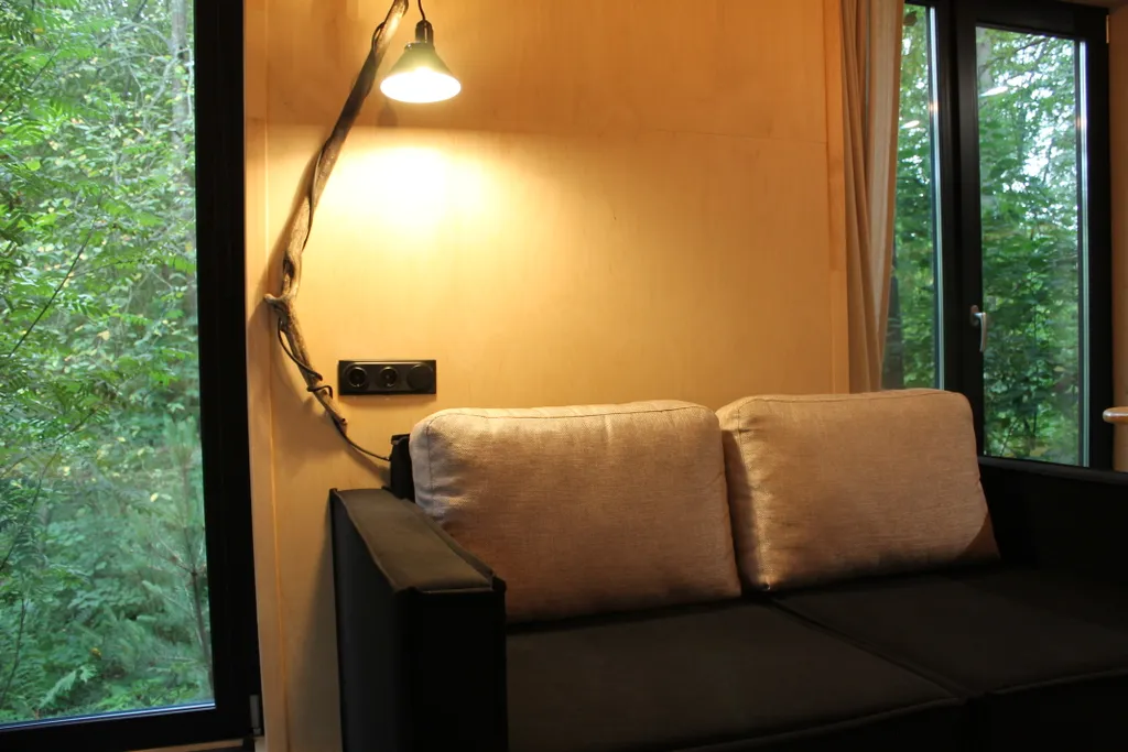 Дом с ванной у панорамных окон и высокой террасой в лесу