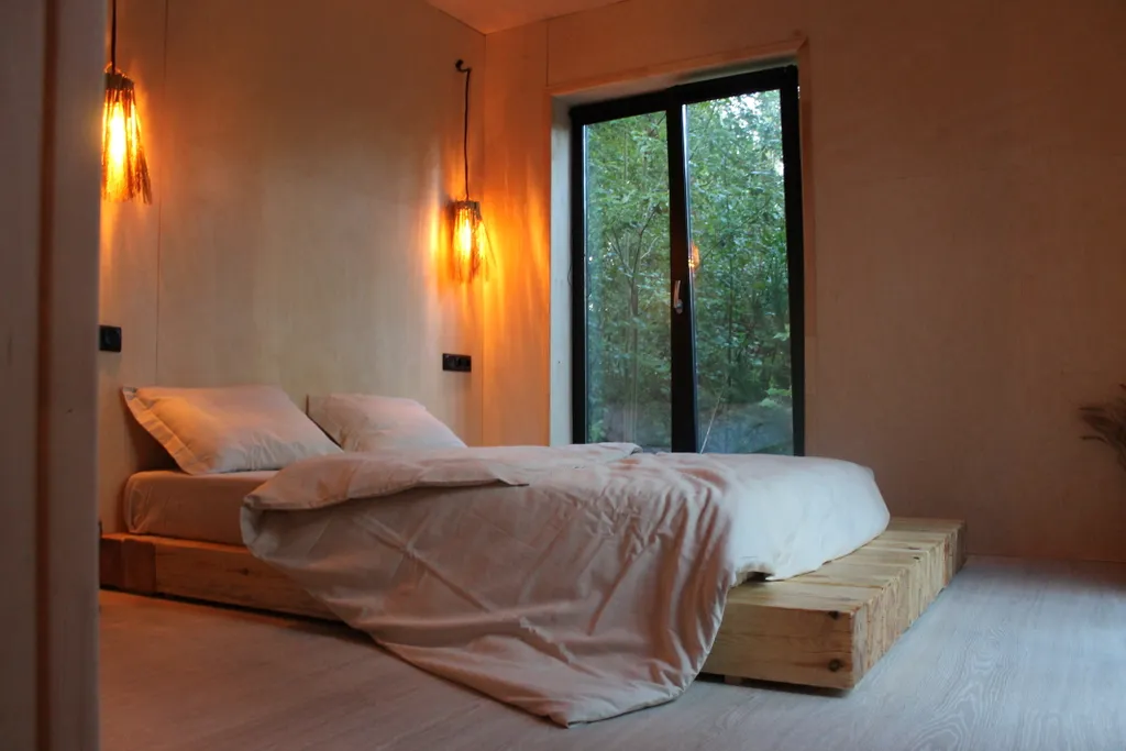 Дом с ванной у панорамных окон и высокой террасой в лесу