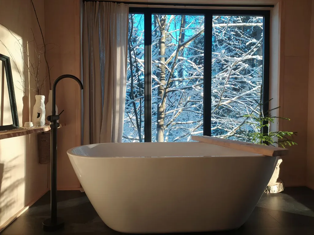 Дом с ванной у панорамных окон и высокой террасой в лесу