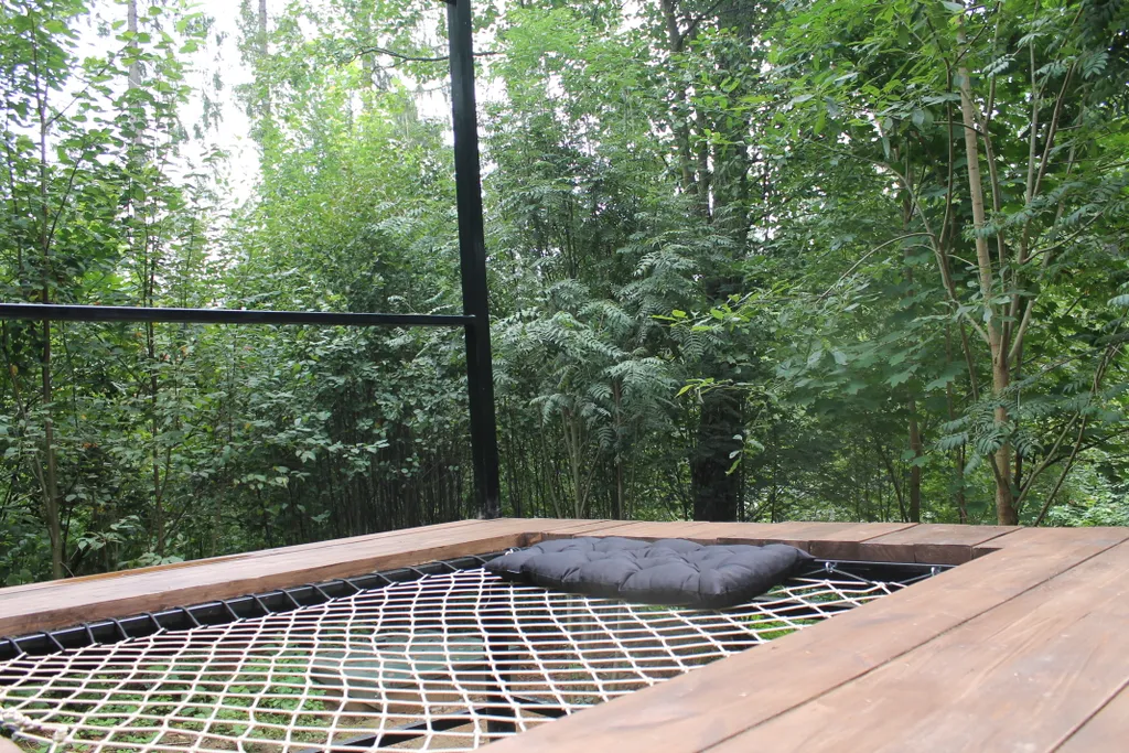 Дом с ванной у панорамных окон и высокой террасой в лесу