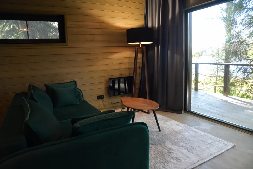 Дом с панорамными окнами в чаще леса у берега реки