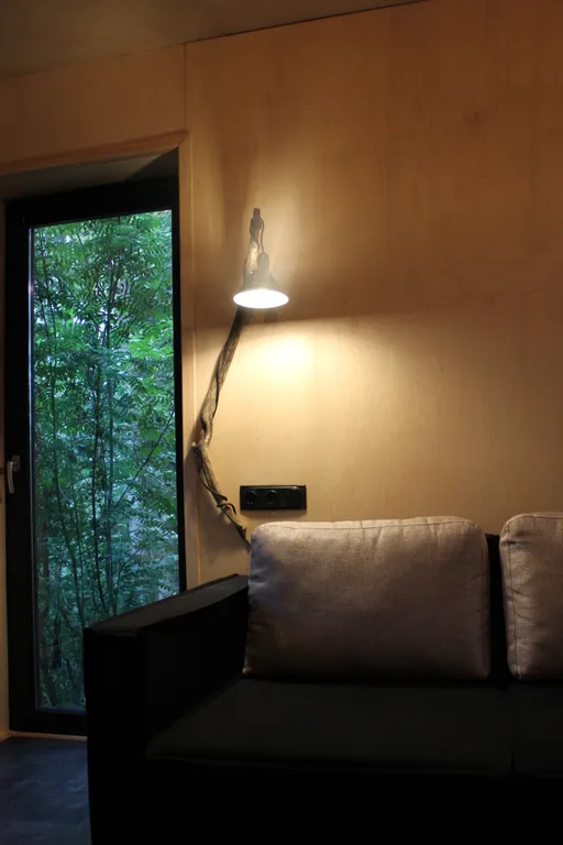 Дом с ванной у панорамных окон и высокой террасой в лесу